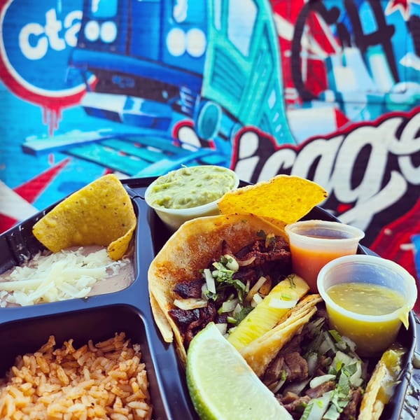 Chicago Taco Authority's taco platter with rice, beans, guacamole, and salsa against a colorful mural.