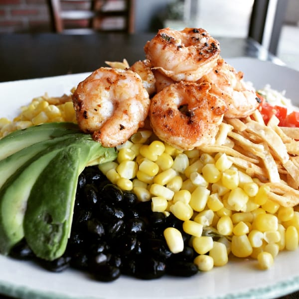 Grilled shrimp atop a colorful Mexican salad with corn, black beans, avocado, and tortilla strips.